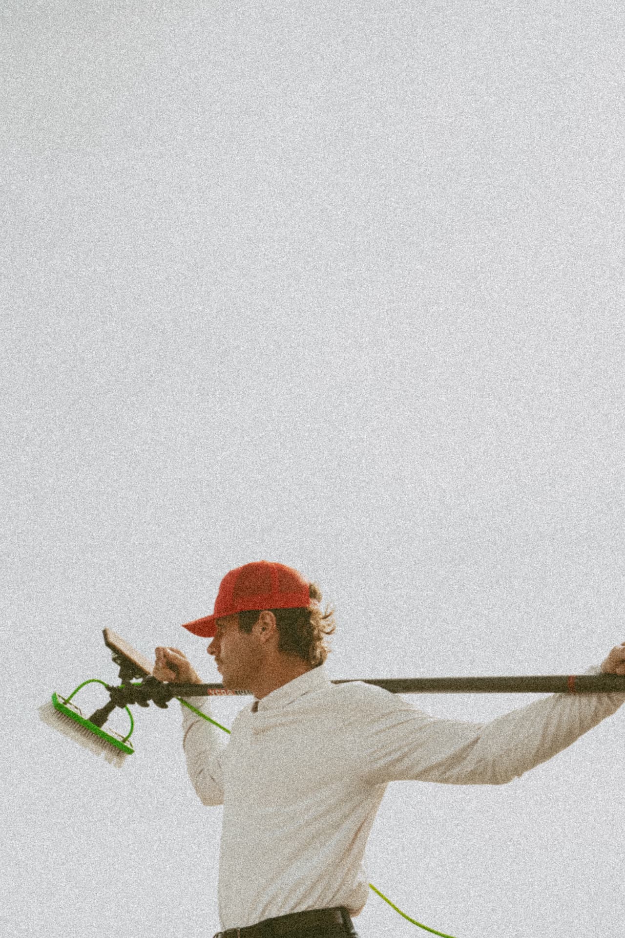 Stoked technician carrying a water-fed pole between jobs