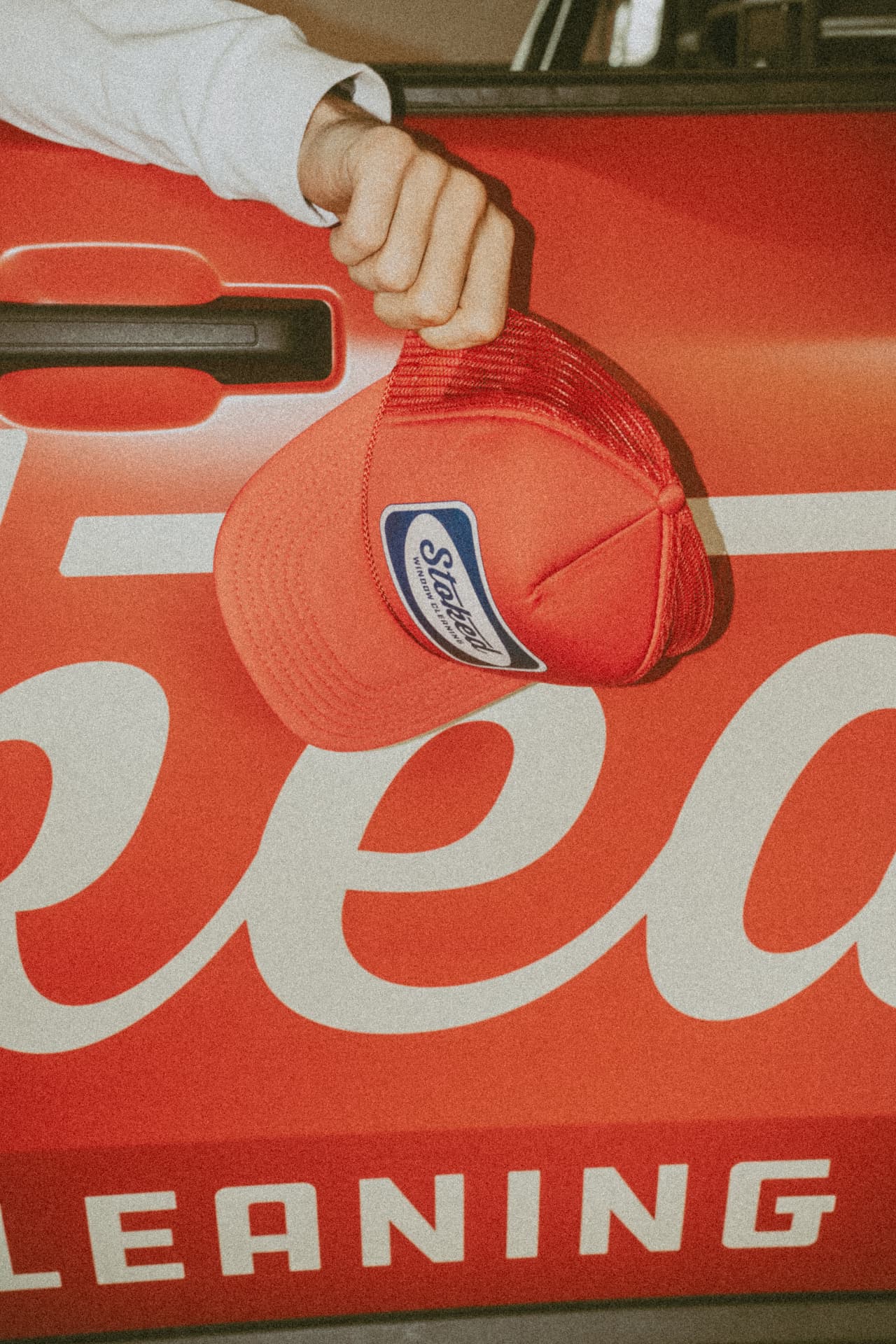 Stoked Window Cleaning cap held against the branded truck